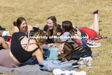 A group of young women take advantage of the nice weather and lay out and visit on the green space b