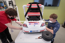 UNL engineering student Ethan Bowles, right modifies a battery-powered car for four-year-old Dayana 