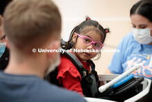 Four-year-old Dayana Torres looks at UNL engineering student Ethan Bowles, left, while being strappe