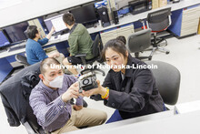 Kuan Zhang, left, discusses a circuit board with Chong Yu in Zhang’s IoT and AI lab. College of En