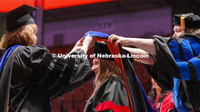 Kylin Flothe’s doctoral hood is lowered into place. Graduate commencement in Pinnacle Bank Arena. 
