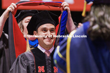 Moises Padilla smiles as his doctoral hood is lowered over his head. Graduate commencement in Pinnac