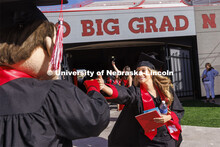 A graduate is greeted by Herbie Husker with a fist-bump. UNL undergraduate commencement in Memorial 