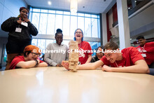 Attendees take turns removing blocks during a game of Jenga at the Nebraska College Preparatory Acad