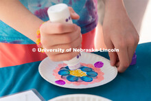 Discovery Day attendees create flower patterns on a plate using an array of colors. The East Campus 