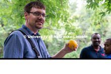 Professor Derek Heeren holds up an orange during his Irrigation Laboratory and Field Course class tr
