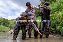 Students work together to set up a device used to measure water flow rates during Professor Derek He