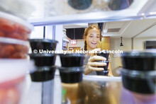Brenna Mazour, a senior in psychology and dietetics, rearranges containers of shredded cheese in the