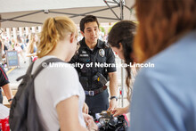 Officer Agustin Champion talks with students at the UNL Police Department booth before letting them 