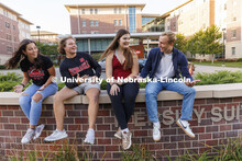 Students seated on a brick wall outside of University Suites Residence Hall. Housing Photo Shoot in 