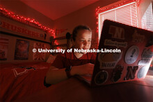 A student studies by the glow of red christmas lights in their University Suites Residence Hall room