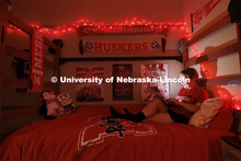 A student studies by the glow of red christmas lights in their University Suites Residence Hall room
