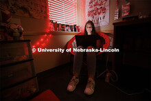 A student studies by the glow of red christmas lights in their University Suites Residence Hall room