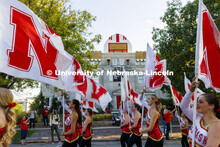 The Cornhusker Marching Band color guard has a super fan peeking out above the Alpha Tau Omega house