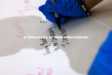 Mona Miller, a sophomore from Omaha, writes on a poster at the event. Volunteers assemble hunger kit