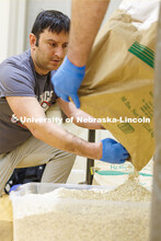 Andrew Brown helps pour the last of a large sack of oatmeal into a container for the volunteers to u