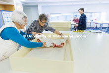 Volunteers Loris Purtzer, left, and Alice Lorenz carefully pack a quilt for storage. Quilt Center. F