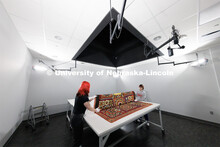 Student workers Olivia Fiore, left, and Inas Hskan, fold a quilt after it was photographed.  The qui