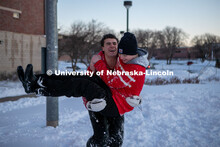 Two friends jump in each others arms while their friends play volleyball in the snow on Thursday out