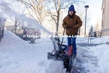Jessica Roberts, a landscape assistant with Landscape Services, snow blows the sidewalk outside Poun
