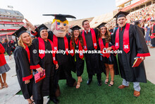 A group of grads pose with Herbie for a photo. Undergraduate commencement at Memorial Stadium. May 2