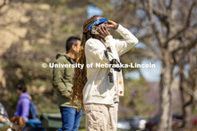 A student catches a glimpse of the eclipse as she talks on the phone on East Campus. April 8, 2024. 