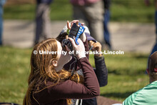 A student attempts to capture a photo of the eclipse using the glasses and her camera on East Campus