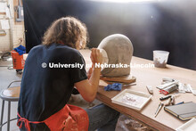 Dawson Adams, a sophomore art student, paints on his sculpture head. Behind the scenes photo for the
