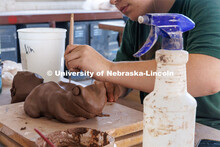 An art student molds her frog sculpture from clay. Behind the scenes photo for the university's new 