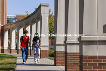 Raikes School students Gannett Bishop and Nina Glick walk along the columns outside of the Kauffman 