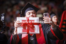 Chancellor’s Scholar Khai Shen Ch’ng takes a selfie with his diplomas as he walks off stage. Win