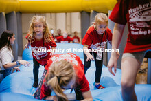 Coralie (Left), a miracle child, and other kids race through a bounce house at the 2025 Huskerthon. 