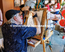 Amanda and Emmitt Perryman laugh as Kirk Kuenzi, a local artist, draws a caricature of them during a