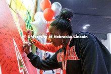 Pauline Karenju of Bennington, Nebraska, signs her name on a large "N" poster during Admitted Studen
