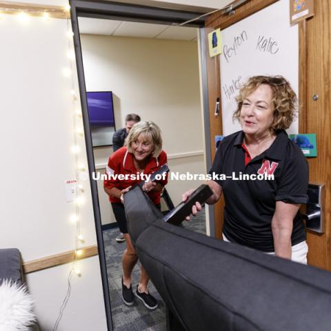Donde Plowman, Executive Vice Chancellor and Chief Academic Officer, and Laurie Bellows, Vice Chancellor for Student Affairs, help carry a futon into a room on city campus' Knoll Residence Hall. August 17, 2017. Photo by Craig Chandler / University