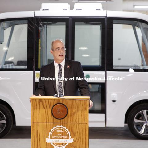 Larry Rilett, Professor of Civil Engineering and Director of Nebraska Transportation Center, addresses the press conference about the roles the university will have in the testing. The automated electric Navya (NAHV-yah) shuttle is displayed at Nebraska