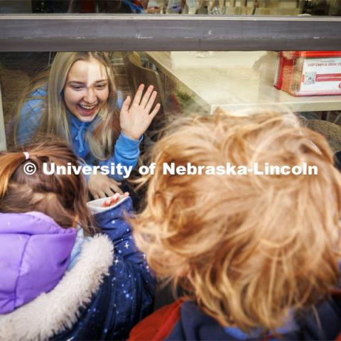 A student waves to the children as the kids look in the windows of the Nebraska East Union. Students in the Ruth Staples Child Development Lab go on a field trip to the Nebraska East Union and a walk around campus. March 1, 2024. Photo by Craig Chandler / University Communication and Marketing.