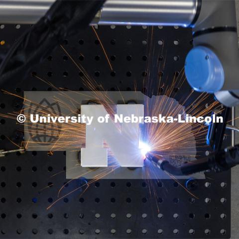 A robotic welder at Nebraska Innovation Studio welds a Nebraska N to a cutout in the shape of Nebraska. March 14, 2024. Photo by Craig Chandler / University Communication and Marketing.